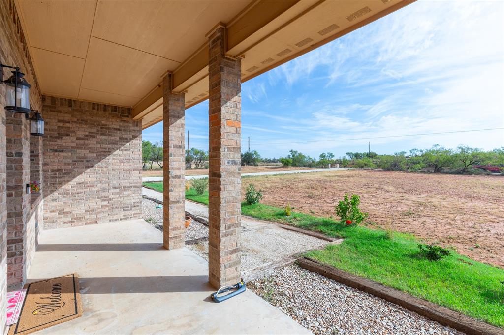 760 Wimberly Road Merkel, TX 79536 - Photo 6 of 35 Covered porch featuring brick columns and walls, concrete flooring, and exterior wall lanterns