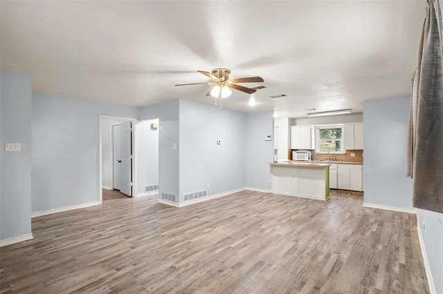a view of kitchen and empty room with wooden floor