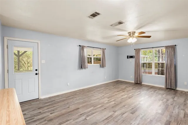 a view of an empty room with a window and wooden floor