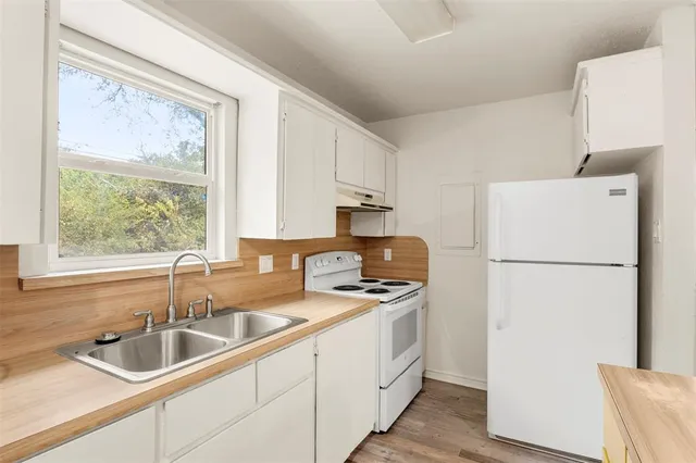 a kitchen with a refrigerator a sink and white cabinets