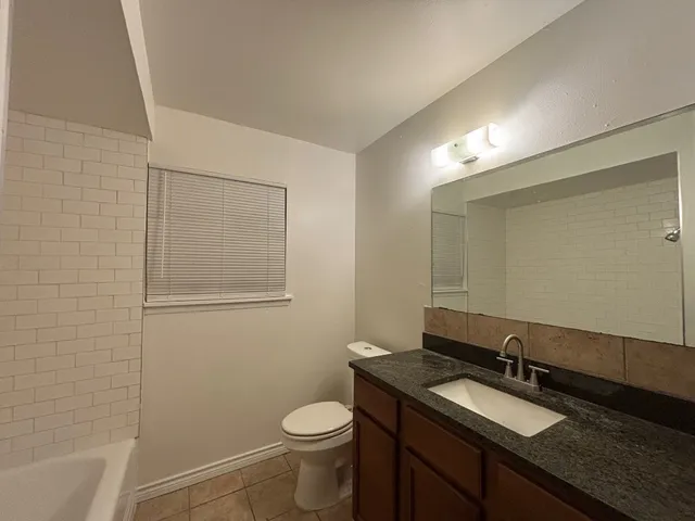 a bathroom with a granite countertop sink toilet and mirror