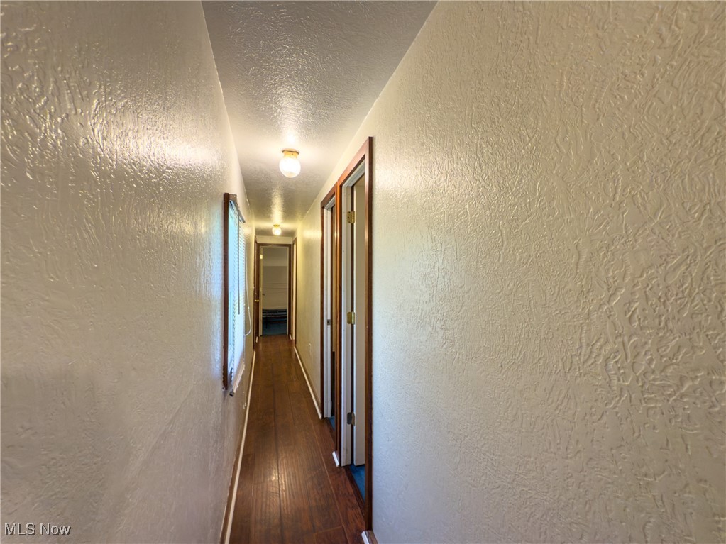 36475 Kinney Ridge Road Woodsfield, OH 43793 - Photo 18 of 50 Corridor with dark wood finished floors, a textured wall, and a textured ceiling
