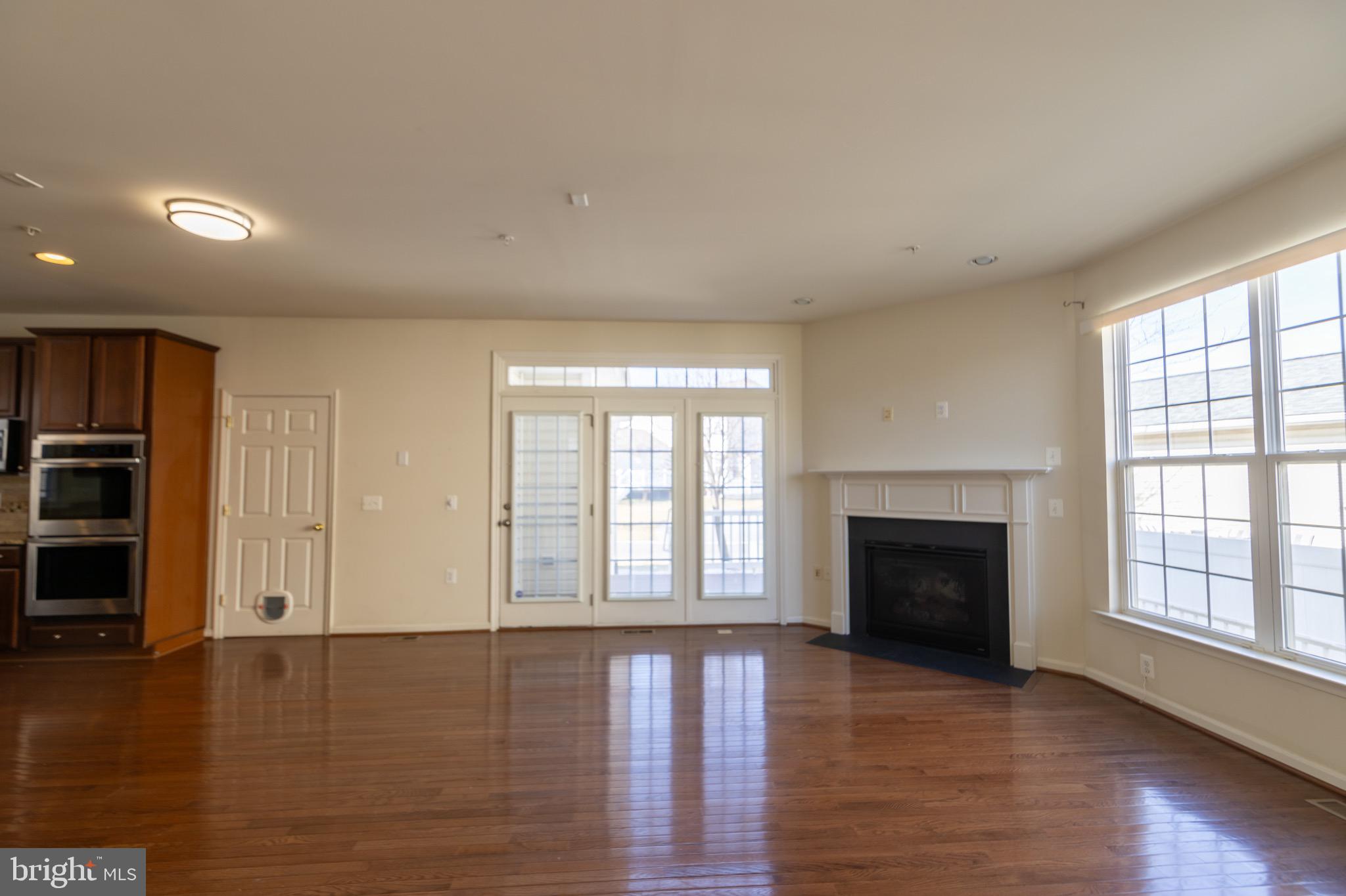 9814 Traver Street Bowie, MD 20721 - Photo 65 of 75 an empty room with wooden floor fireplace and windows