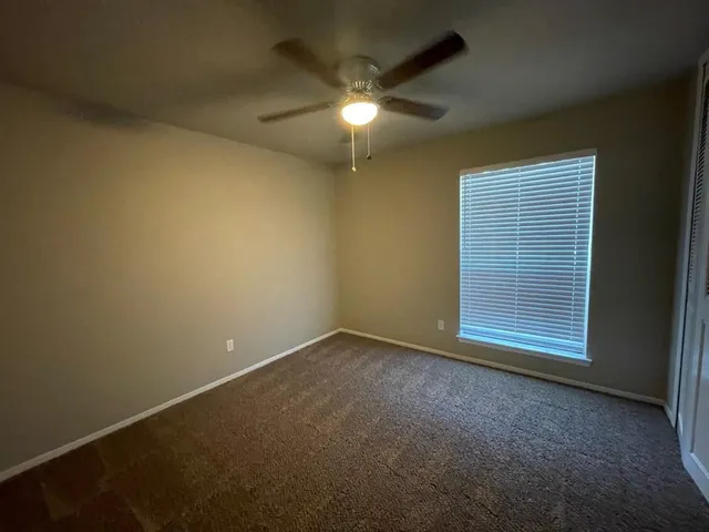 an empty room with a ceiling fan and a window