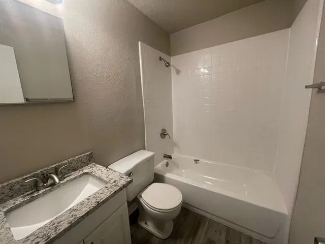 a bathroom with a granite countertop sink toilet and shower