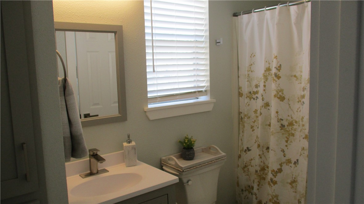6702 Everhart Road, Unit H109 Corpus Christi, TX 78413 - Photo 13 of 18 a bathroom with a sink a toilet and a mirror