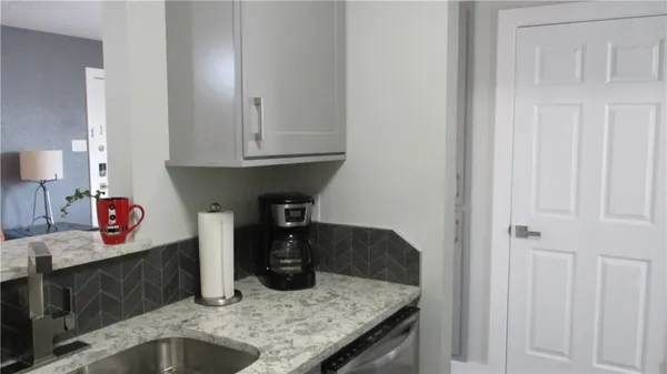 a kitchen with granite countertop a sink and white cabinets