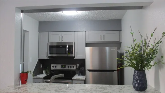 a kitchen with stainless steel appliances a refrigerator and a potted plant