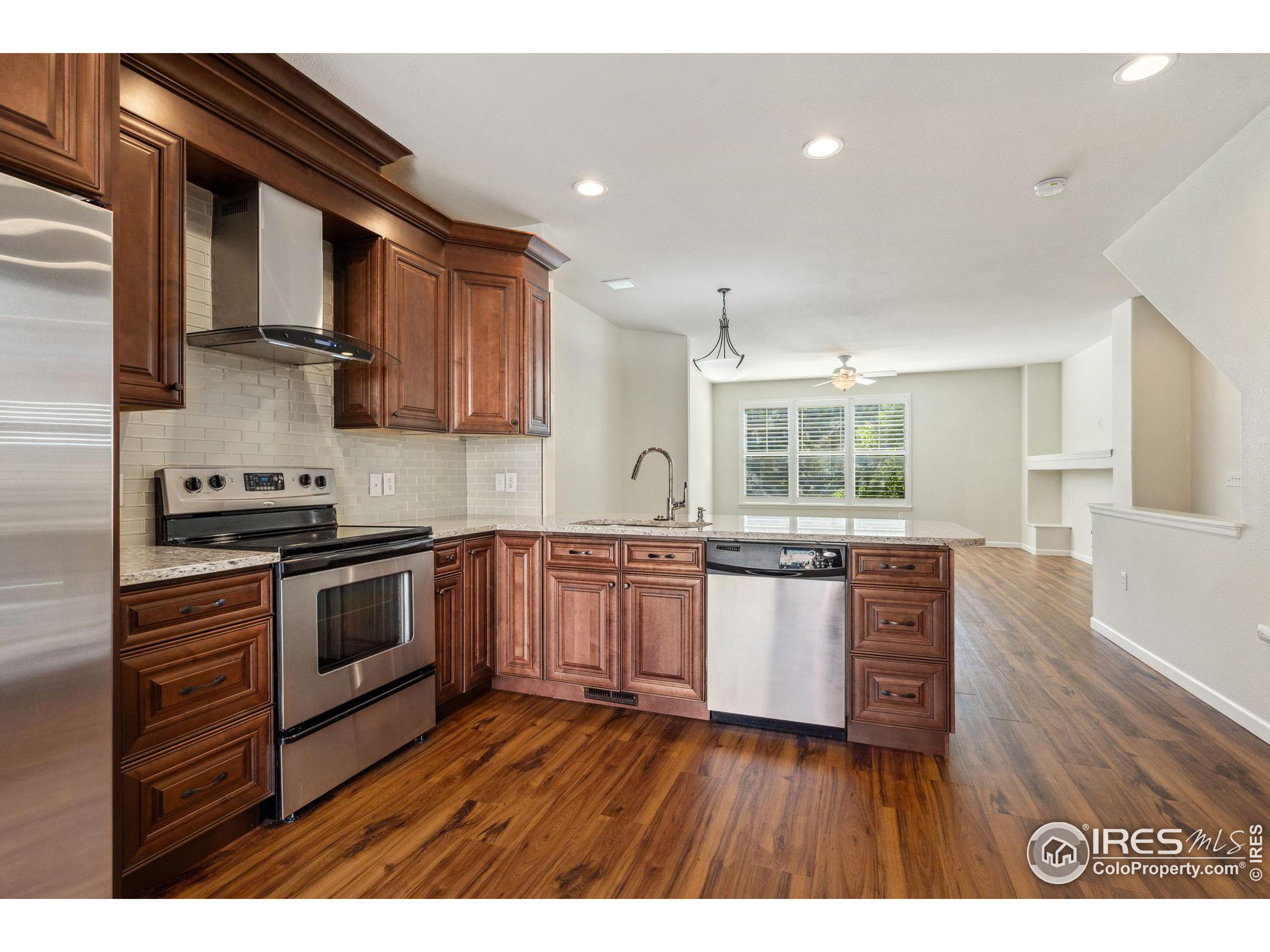 a kitchen with granite countertop wooden floors and stainless steel appliances