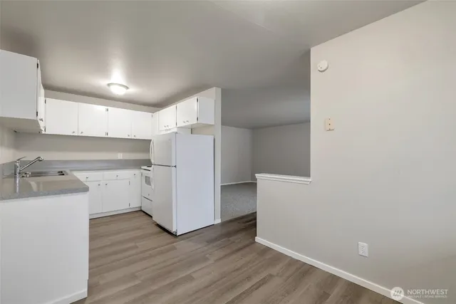 a kitchen with wooden floor and cabinets