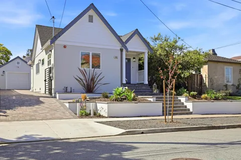a front view of a house with garage and plants
