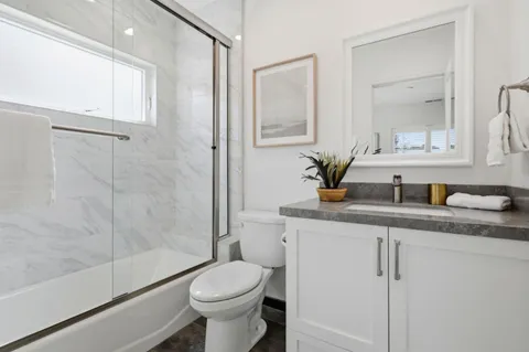 a bathroom with a granite countertop sink a toilet and shower