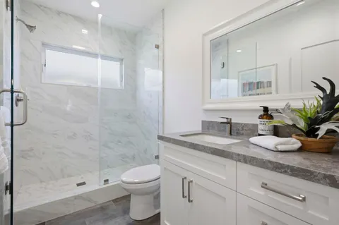 a bathroom with a granite countertop sink a toilet and shower