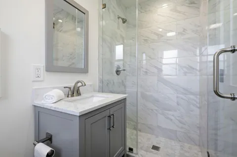 a bathroom with a sink vanity granite shower and a mirror