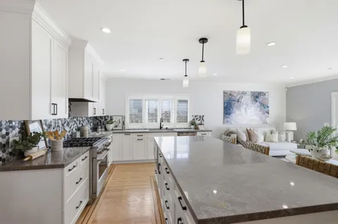 a large kitchen with lots of counter space white cabinets and stainless steel appliances
