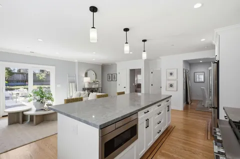 a large kitchen with kitchen island a large counter space a sink appliances and living room view