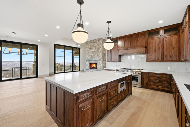 2155 East Wrangler Road Kamas, UT 84036 - Photo 62 of 62 Kitchen featuring open floor plan, backsplash, a stone fireplace, a center island with sink, and light wood finished floors