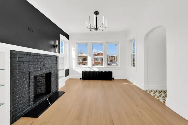 a living room with stainless steel appliances granite countertop a fireplace and a refrigerator