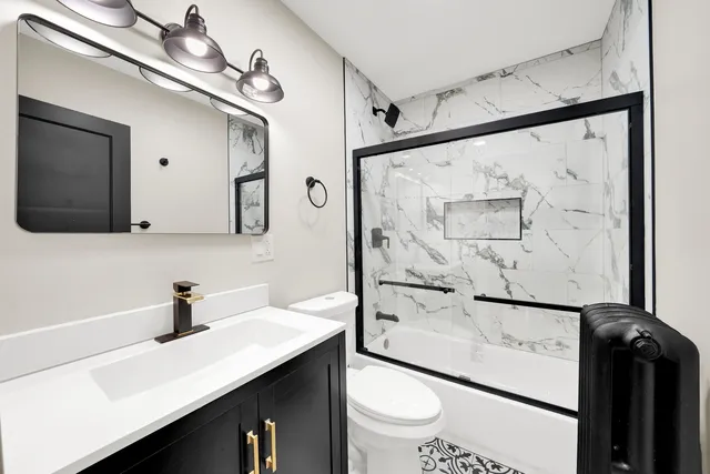 a bathroom with a sink a toilet a mirror and shower