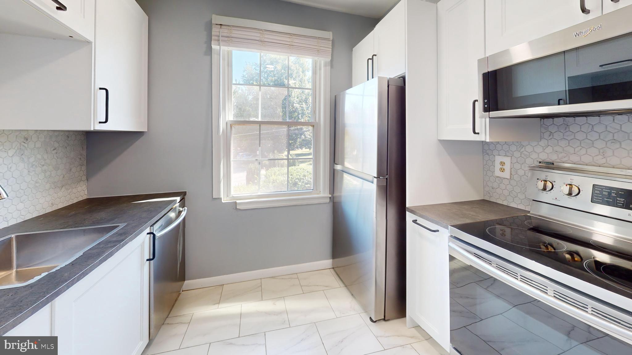 2203 Washington Avenue, Unit 102 Silver Spring, MD 20910 - Photo 2 of 13 a kitchen with granite countertop a stove sink and refrigerator