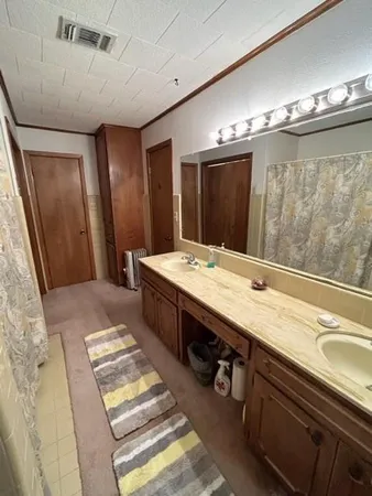 a bathroom with double vanity sinks a large mirror and a shower
