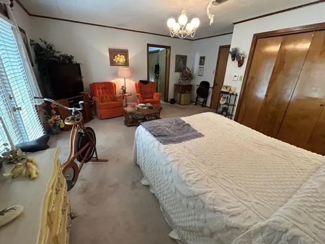 a bedroom with bed a chair and a chandelier