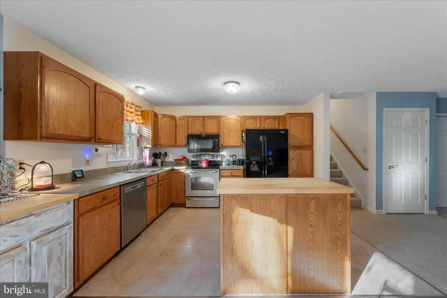 a kitchen with a sink a refrigerator a stove top oven a counter space and cabinets