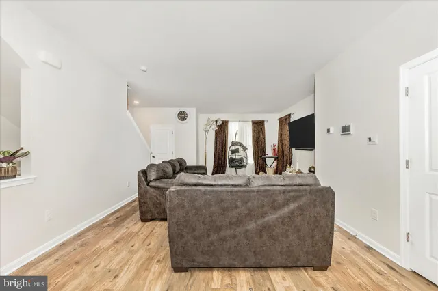 a living room with furniture a flat screen tv and a wooden floor