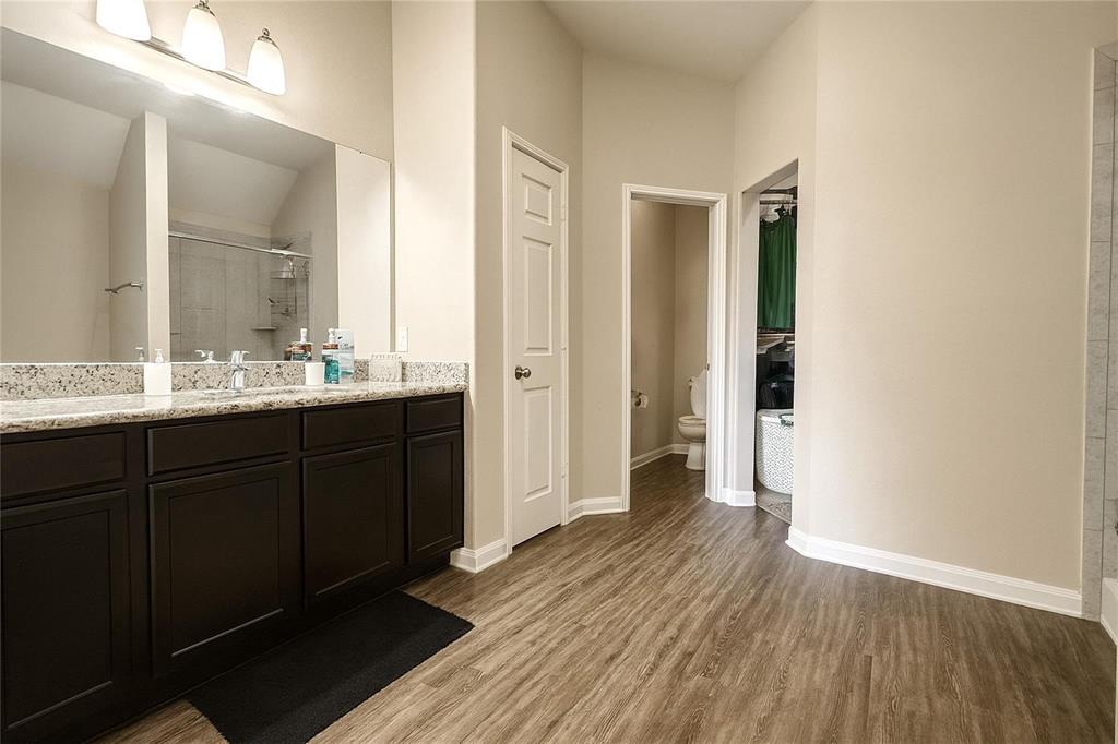 1837 Rialto Lane Crowley, TX 76036 - Photo 18 of 19 Bathroom featuring a dual vanity with granite-style countertop, dark wood-finish cabinetry, and wood-finish flooring