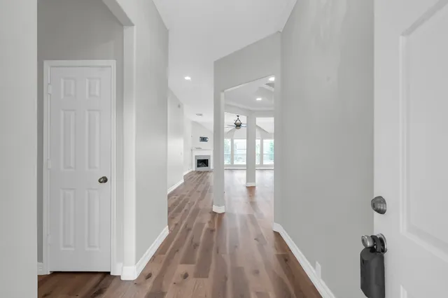 a view of an empty room with wooden floor fireplace and a window