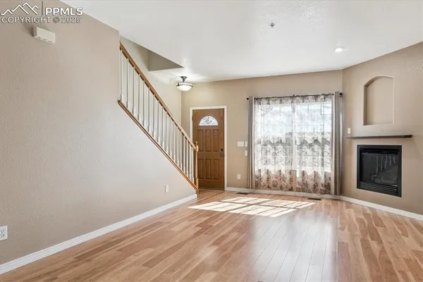 a view of an empty room with wooden floor and a window