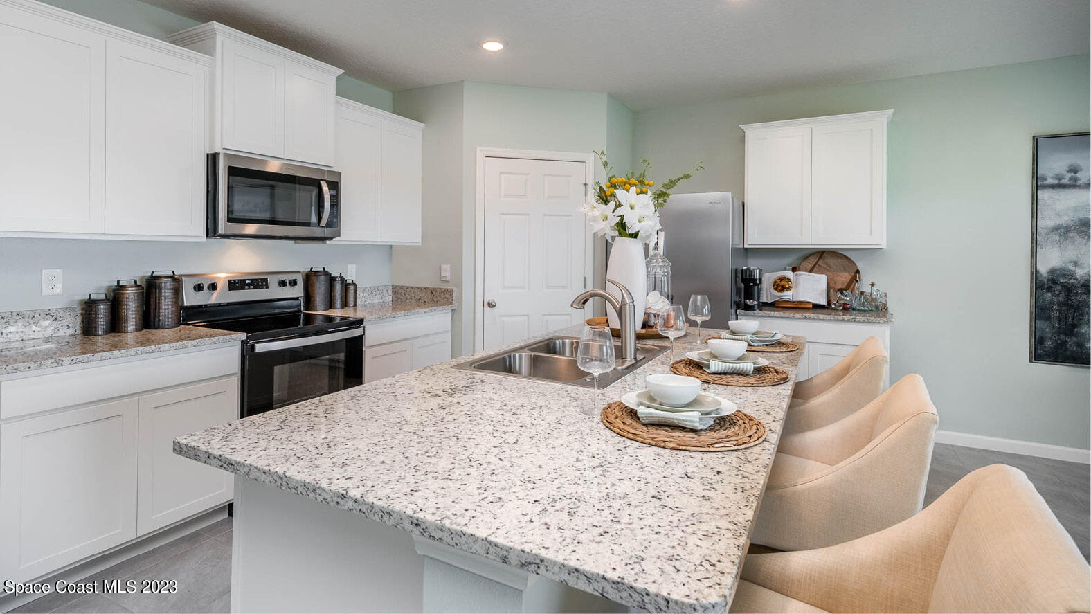 4954 Quartz Place Grant-Valkaria, FL 32949 - Photo 2 of 48 a kitchen with stainless steel appliances kitchen island granite countertop a sink dishwasher stove and microwave with wooden floor