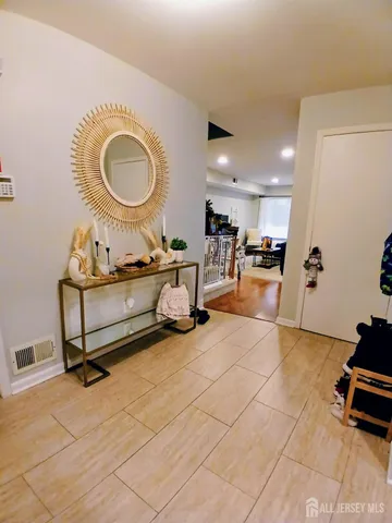 a living room with furniture a mirror and a view of kitchen