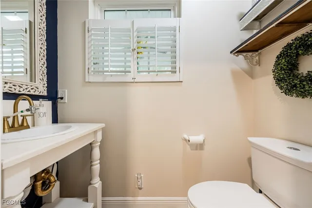 a bathroom with a sink a toilet and a window