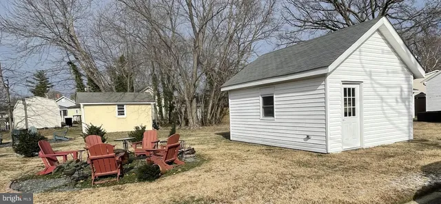 a view of a white house with a large tree bed and wooden fence