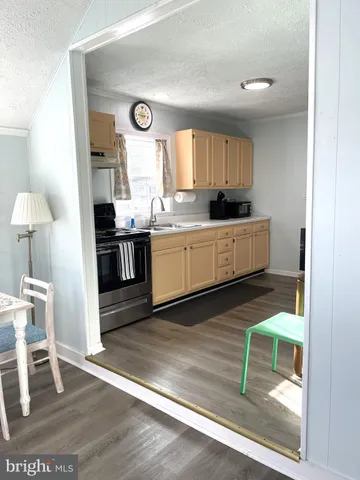 a large kitchen with a wooden floor and a view of living room
