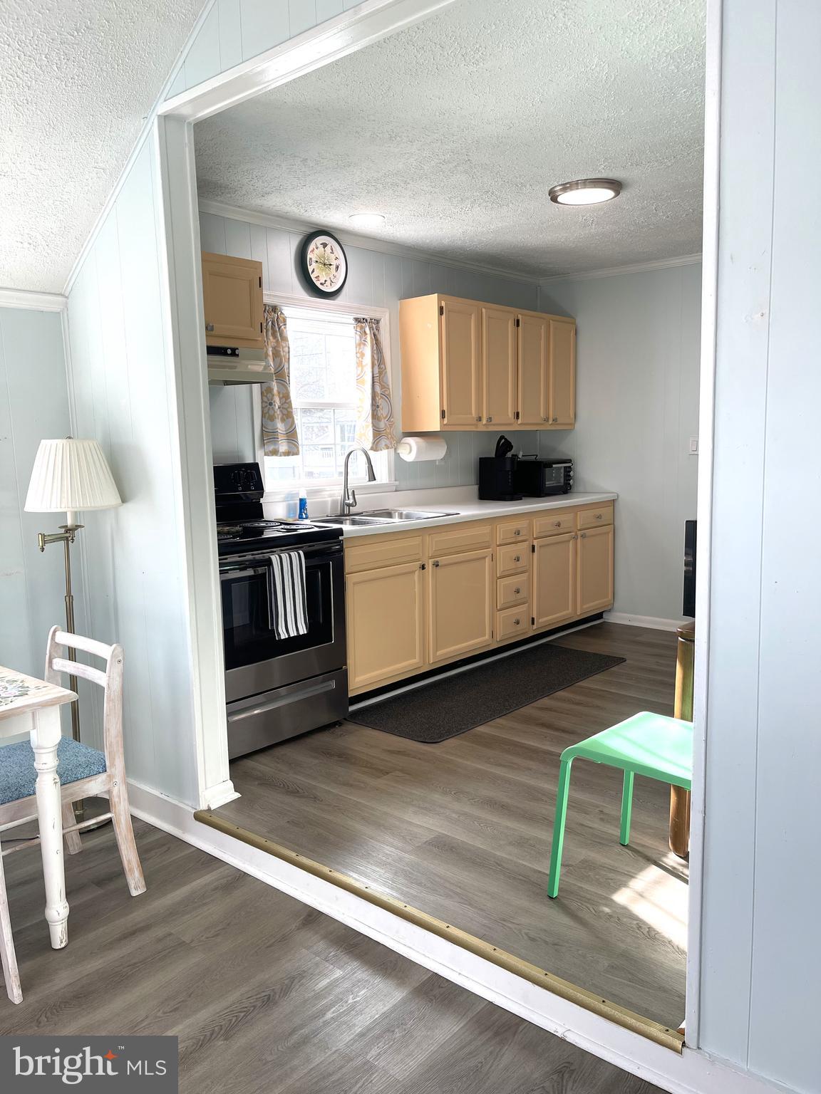 221 Madison Street Colonial Beach, VA 22443 - Photo 6 of 28 a large kitchen with a wooden floor and a view of living room
