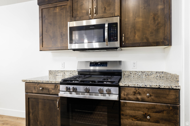 3157 Deseret Drive St. George, UT 84790 - Photo 6 of 24 Stainless steel range with an overhead microwave, dark wood cabinetry, and granite countertops