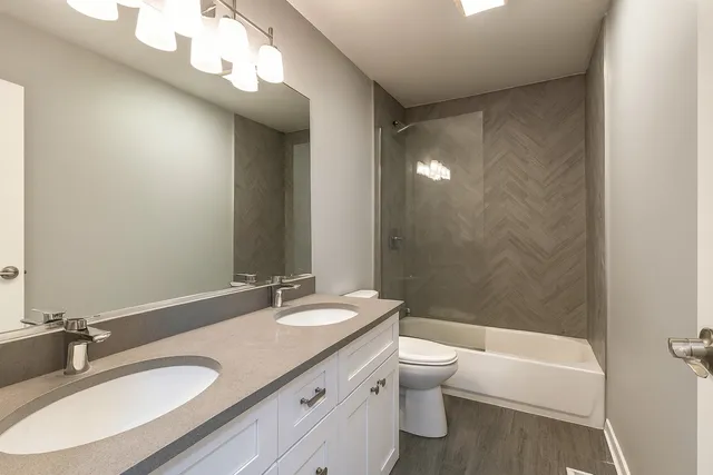 a bathroom with a granite countertop sink a toilet a light fixture and a mirror