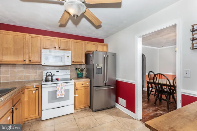 a kitchen with stainless steel appliances granite countertop a refrigerator a stove and a sink with wooden floor
