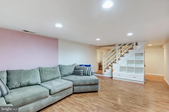 a living room with furniture and stairs with wooden floor