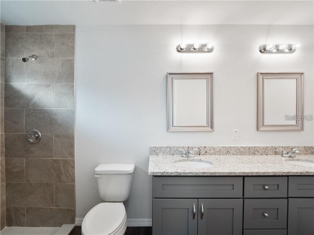 17399 Southwest 25th Circle Ocala, FL 34473 - Photo 16 of 22 a bathroom with a granite countertop toilet a sink and mirror