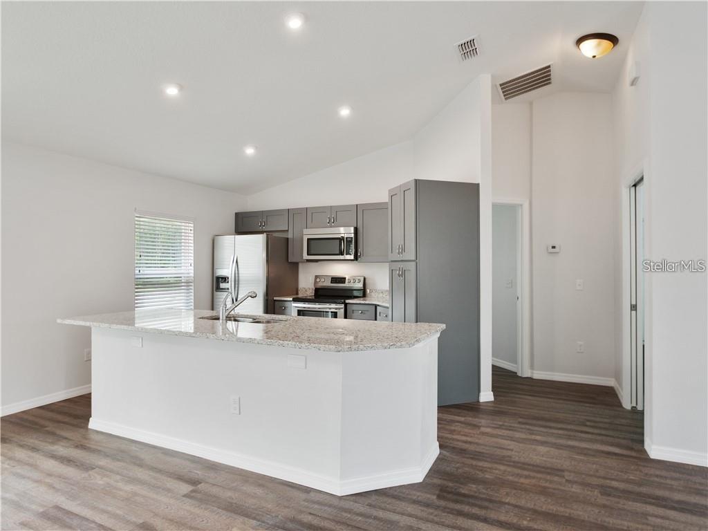 17399 Southwest 25th Circle Ocala, FL 34473 - Photo 3 of 22 a large kitchen with stainless steel appliances a refrigerator a stove a sink dishwasher and wooden floor
