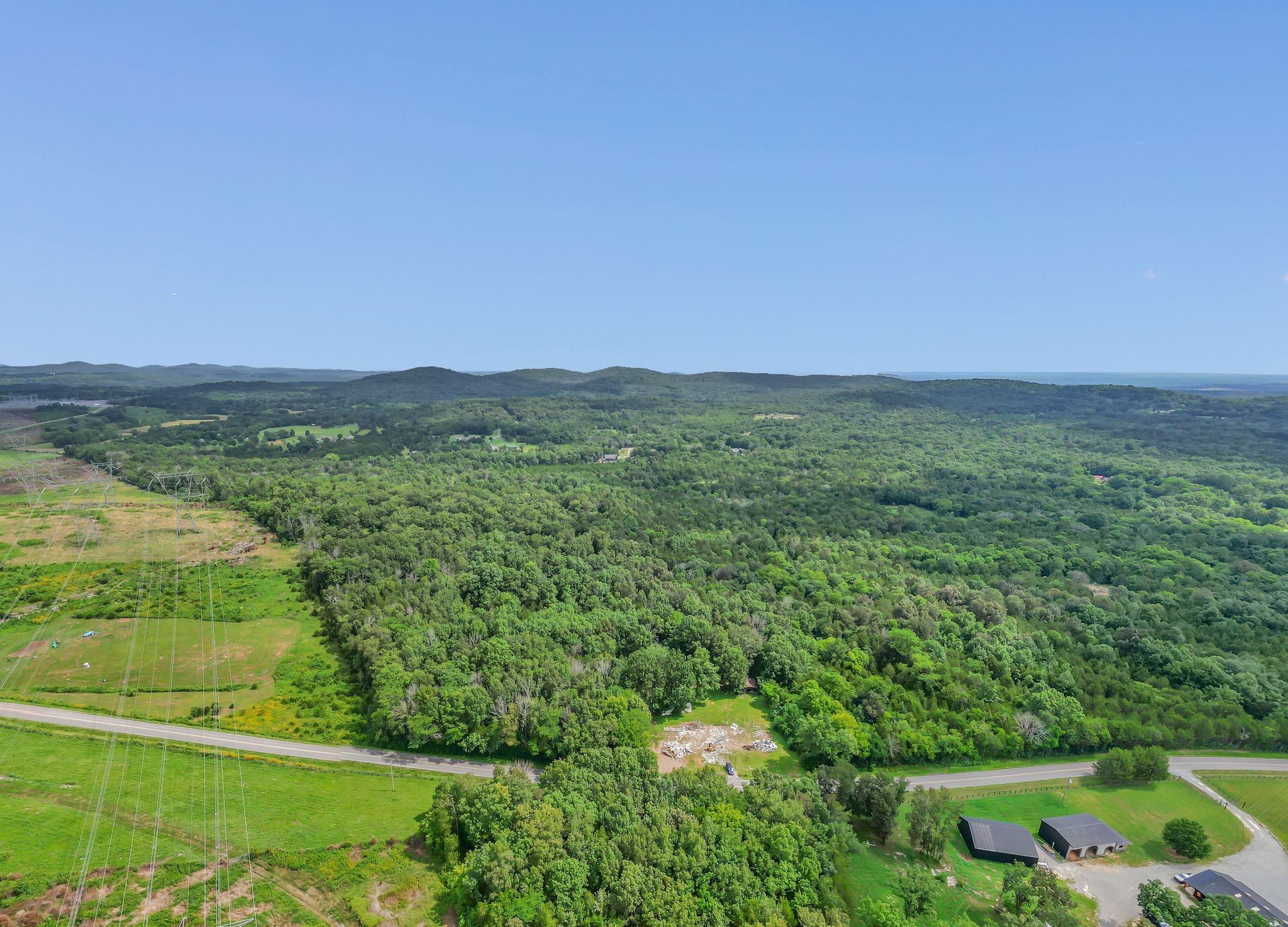 a view of a lush green outdoor space with a swimming pool and valleys in the background