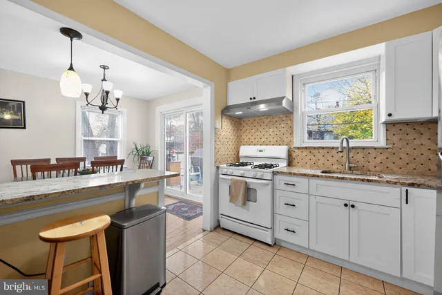 a kitchen with stainless steel appliances granite countertop a sink a stove a refrigerator and island with wooden floor