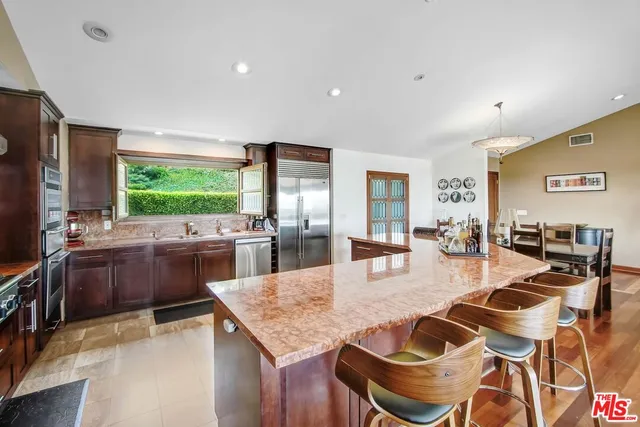 a dining hall with stainless steel appliances kitchen island granite countertop a dining table and chairs