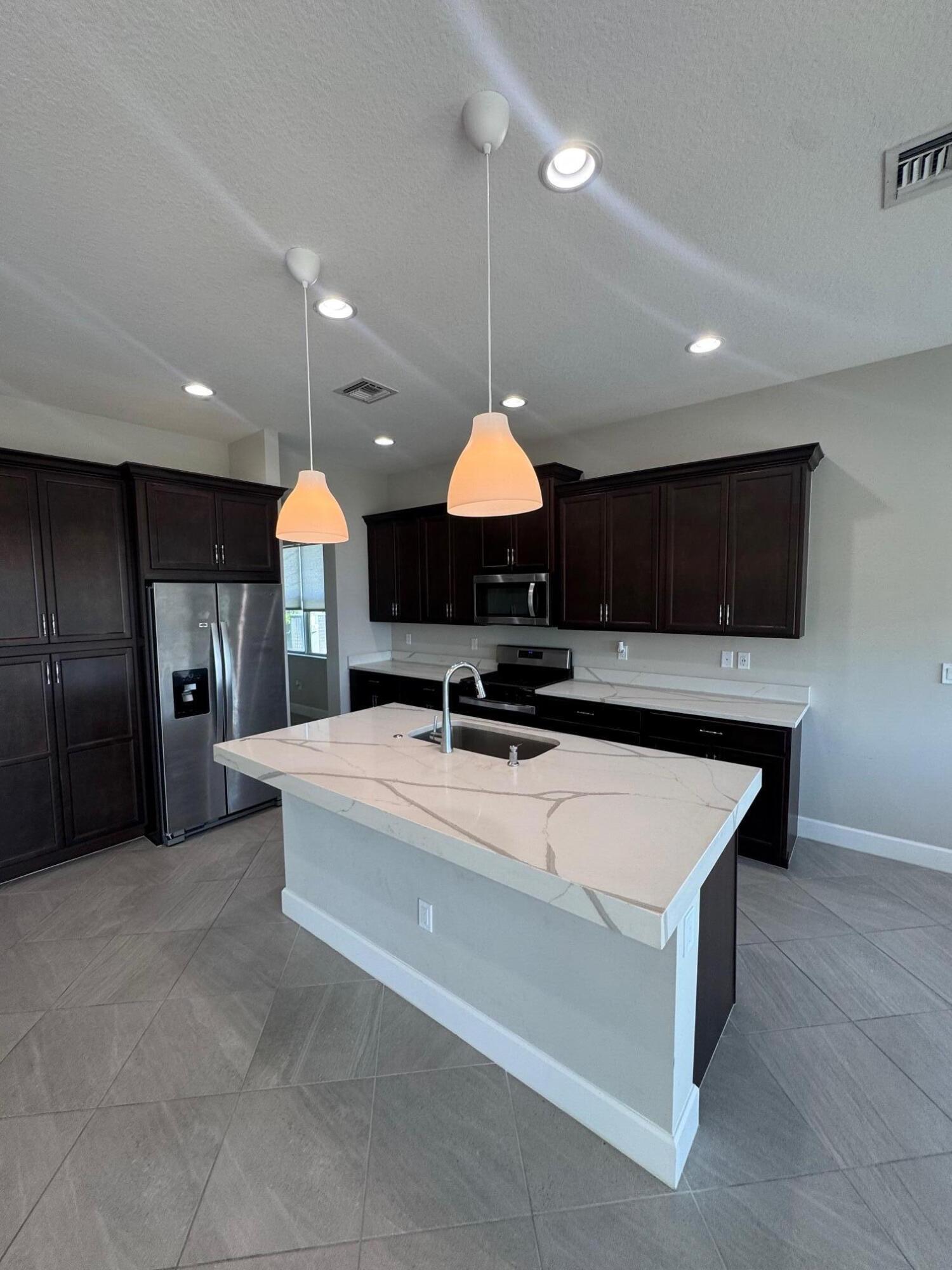 5585 Macoon Way, Unit 5585 Loxahatchee, FL 33470 - Photo 4 of 14 a large kitchen with stainless steel appliances granite countertop a sink a stove and a refrigerator