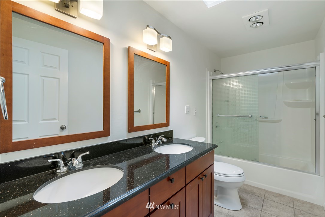 15612 Renton Issaquah Road Southeast Renton, WA 98059 - Photo 13 of 30 a bathroom with a granite countertop sink toilet a mirror a vanity and shower