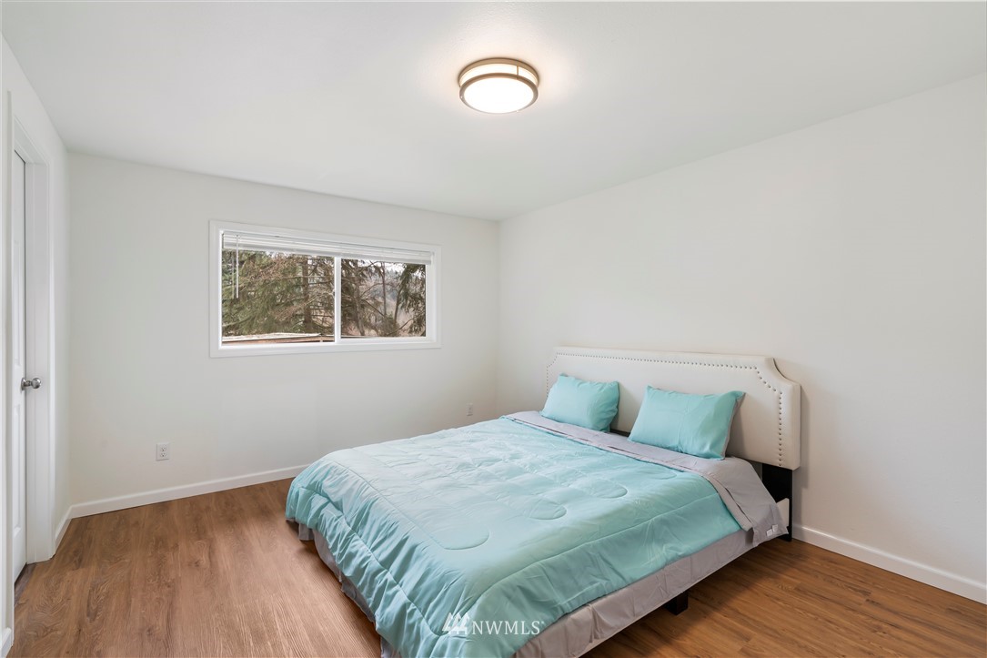 15612 Renton Issaquah Road Southeast Renton, WA 98059 - Photo 18 of 30 a bedroom with a bed and a wooden floor
