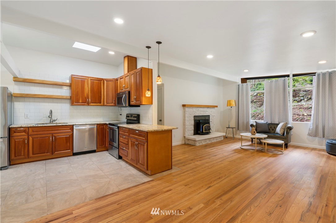 15612 Renton Issaquah Road Southeast Renton, WA 98059 - Photo 10 of 30 a large kitchen with stainless steel appliances granite countertop a stove a sink dishwasher and a fireplace with wooden floor